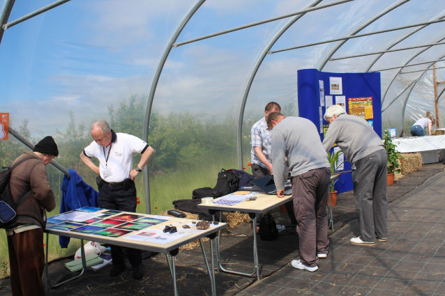 Inside a large poly tunnel Ken shows a visitor some photographs of Aurora, Noctilucent clouds and other pictures taken by DAS members, while 3 other DAS members organise the second display table.